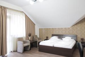 a bedroom with a bed and chairs and a window at Hotel Rao in Cluj-Napoca +21 photos