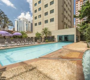 a swimming pool in front of a building at Flat Hotel de luxo em Moema, São Paulo in São Paulo
