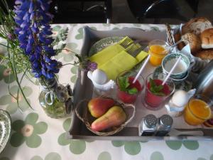 Bed and breakfast De Zwanebloem في إلبلورخ: صينية طعام على طاولة مع فاكهة ومشروبات