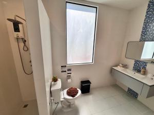 a bathroom with a toilet and a window and a sink at Phuket Muay Thai Hotel Rawai Beach in Rawai Beach
