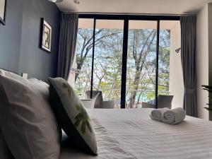 a bedroom with a bed with pillows and a large window at Phuket Muay Thai Hotel Rawai Beach in Rawai Beach