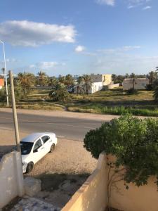 a white car parked on the side of a road at Aghir DJERBA Erdgeschosswohnung in Al Ḩaddādah