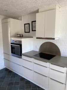 a kitchen with white cabinets and a microwave at Ellemose Bed and Breakfast in Lemvig +8 photos