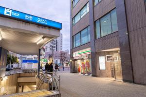 a city street with people walking in front of a building at HP Jōshin in Nagoya