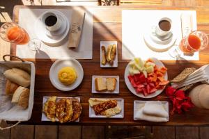 a table with plates of food and cups of coffee at Pousada Unaí - Casa Flor in Fernando de Noronha