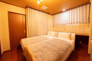 a bedroom with a large bed and a window at HP Jōshin in Nagoya