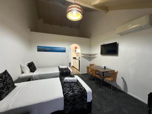 a room with two beds and a table and a kitchen at Chelmswood Motel Taupo in Taupo