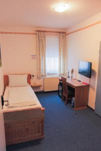 a bedroom with a bed and a desk with a computer at Hotel Stangl in Hamm