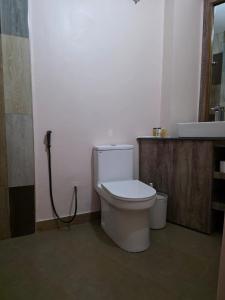 ein Badezimmer mit weißer Toilette und Waschbecken in der Unterkunft The CRADLE in Daressalam