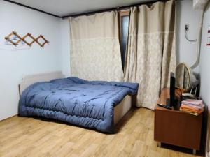 a bedroom with a bed with a blue comforter and a desk at Chuncheon Saemmul Dungji Pension in Chuncheon