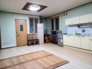 a kitchen with white cabinets and a wooden floor at Chuncheon Saemmul Dungji Pension in Chuncheon