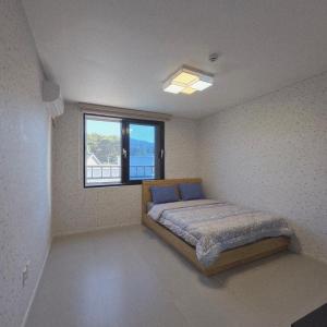 a bedroom with a bed in a room with a window at Gangneung Jitap Pension in Gangneung +19 photos