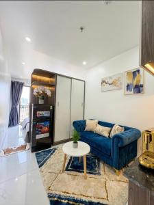 a living room with a blue couch and a table at Rochomes Apartment in Thịnh Châu