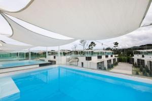 a large swimming pool with a white umbrella over it at Pool Lounge Pension & Glamping in Yangyang