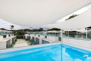 a large swimming pool under a large white umbrella at Pool Lounge Pension & Glamping in Yangyang