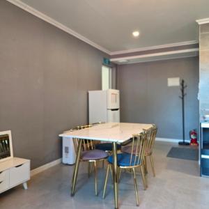 a kitchen with a table and chairs and a refrigerator at Gangneung Moan Pension in Gangneung