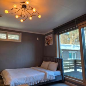 a bedroom with a bed with a chandelier and a window at Gangneung Moan Pension in Gangneung