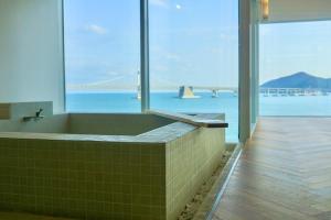 a bathroom with a tub with a view of the ocean at Busan Neouigyejeol in Busan