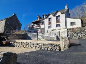 a large white house with a stone wall in front at Les Terrasses de Laguiole in Laguiole