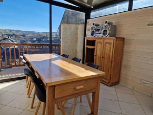a wooden table and chairs in a room with a balcony at Les Terrasses de Laguiole in Laguiole