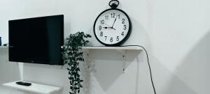 a clock sitting on top of a table next to a tv at FS Homestay Cherating in Kuantan
