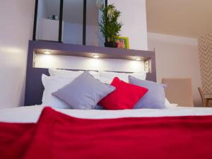 uma cama com almofadas brancas e vermelhas em Studio Premium Zénith Arènes Purpan em Toulouse