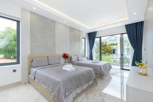 two beds in a bedroom with blue curtains and windows at Villa B2-34 Long Cung in Vung Tau +50 photos