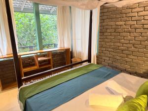 a bedroom with a bed and a brick wall at casa luna villa in Narigama