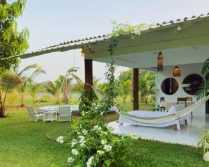 a patio with a hammock and a table and chairs at Ceylon Marley Villa in Talawa