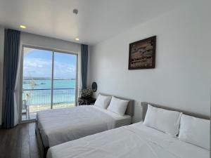two beds in a room with a view of the ocean at Babylon Hotel Phu Quy in Cu Lao Thu +109 photos