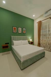 a bedroom with a large bed with a green wall at Mulberry Living in Negombo