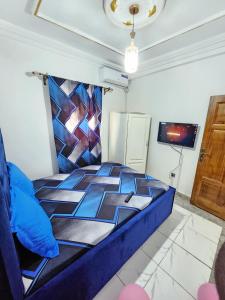a bedroom with a blue bed and a tv at FOKOU House in Yaoundé +5 photos