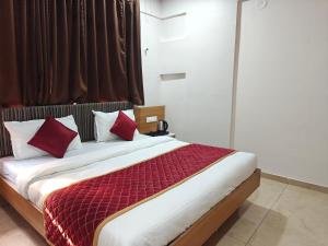a bedroom with a bed with red and white pillows at Hotel Vivank in Kolhapur