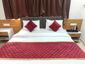 a bedroom with a bed with red pillows at Hotel Vivank in Kolhapur