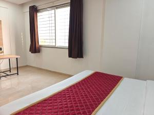 a bedroom with a bed with a red blanket at Hotel Vivank in Kolhapur