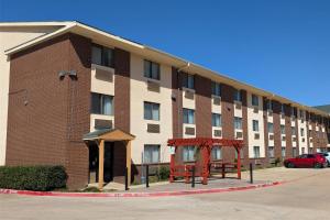 a large brick building with a parking lot in front of it at Quality Inn DFW Airport North in Irving