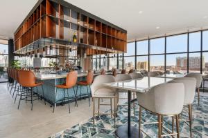 a bar with chairs and tables in a room with windows at Cambria Hotel Nashville Midtown in Nashville