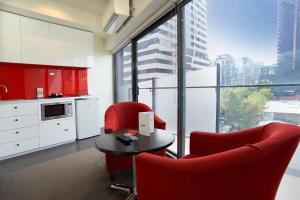 a kitchen with red chairs and a table and a large window at Comfort Apartments on Elizabeth in Melbourne