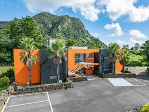 an orange house with a mountain in the background at Dammora Resort in Seogwipo