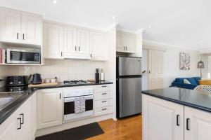 a kitchen with white cabinets and a black refrigerator at Charming CBD cottage - walk everywhere in Mount Gambier