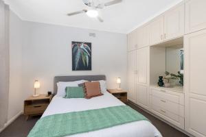 a white bedroom with a bed with a green blanket at Charming CBD cottage - walk everywhere in Mount Gambier