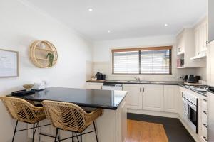 a kitchen with white cabinets and a black counter top at Charming CBD cottage - walk everywhere in Mount Gambier +28 photos