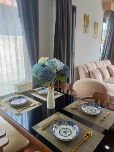 a dining room table with plates and a vase of flowers at Aonang Homie Pool villa in Ao Nang 