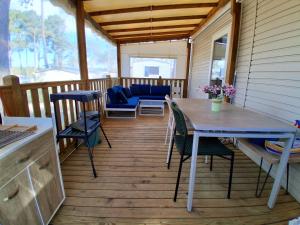 a screened in porch with a table and chairs at CAMPING Les EMBRUNS - 4 ETOILES in Lège-Cap-Ferret