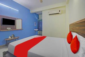 a bedroom with a bed with red pillows and a tv at Hotel O Satya Inn in Karīmnagar