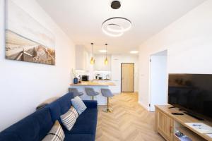a living room with a blue couch and a kitchen at Jarzebinowa Loft III by JumpInHere in Nowy Dwór Mazowiecki