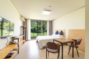 a hotel room with a bed and a desk and a table at Dammora Resort in Seogwipo