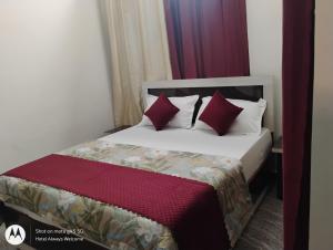 a bedroom with a bed with red and white pillows at Hotel Always Welcome in Nākuri