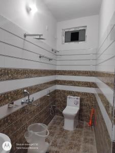 a bathroom with a toilet and a tv on the wall at Hotel Always Welcome in Nākuri