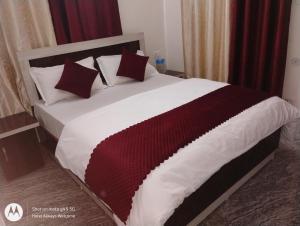 a large bed with red and white sheets and pillows at Hotel Always Welcome in Nākuri